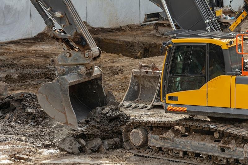 A yellow excavator parked on a dirt construction site
